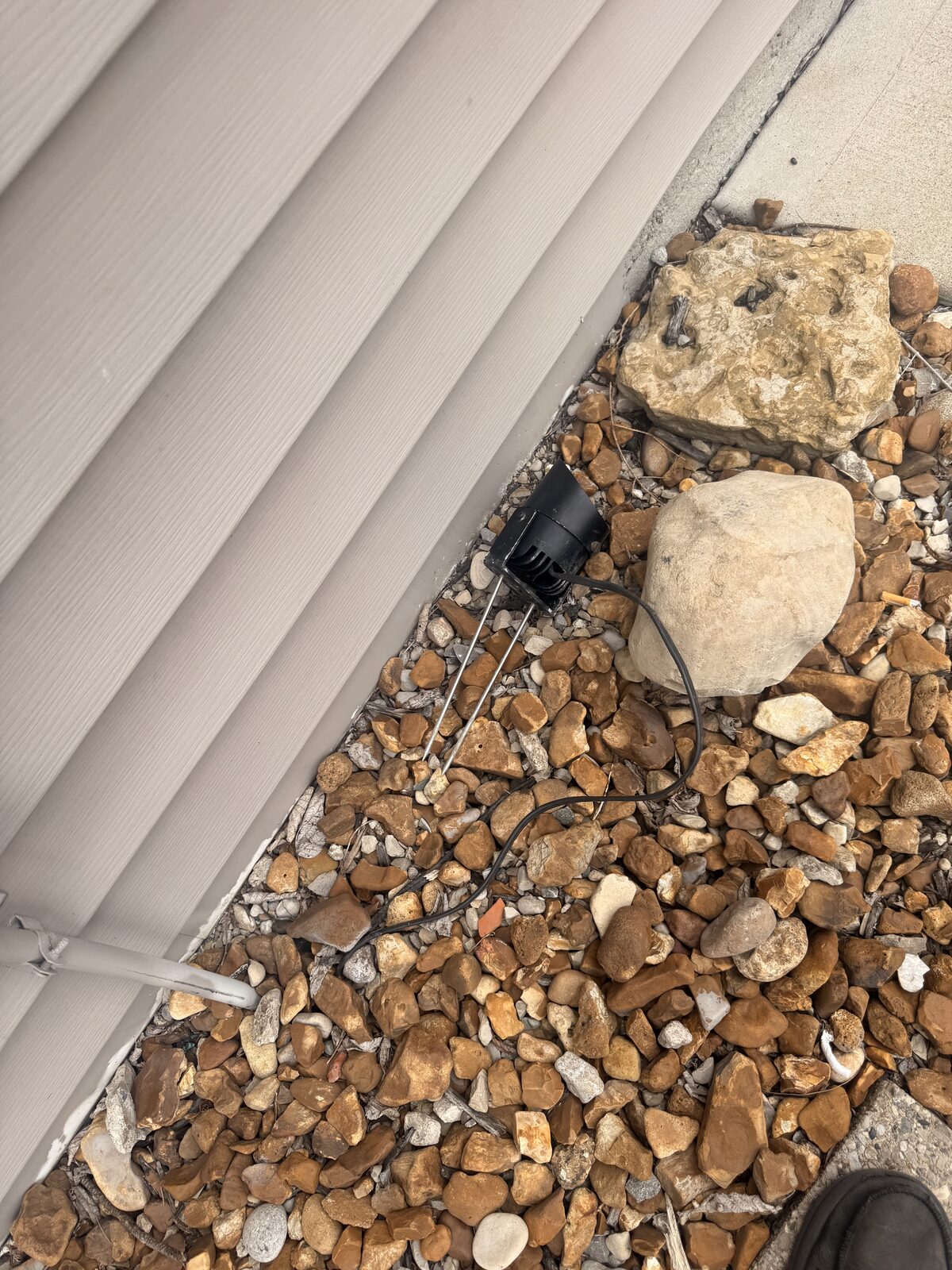 Previous installer's uplight fixture lying loose in the gravel at Cozy's