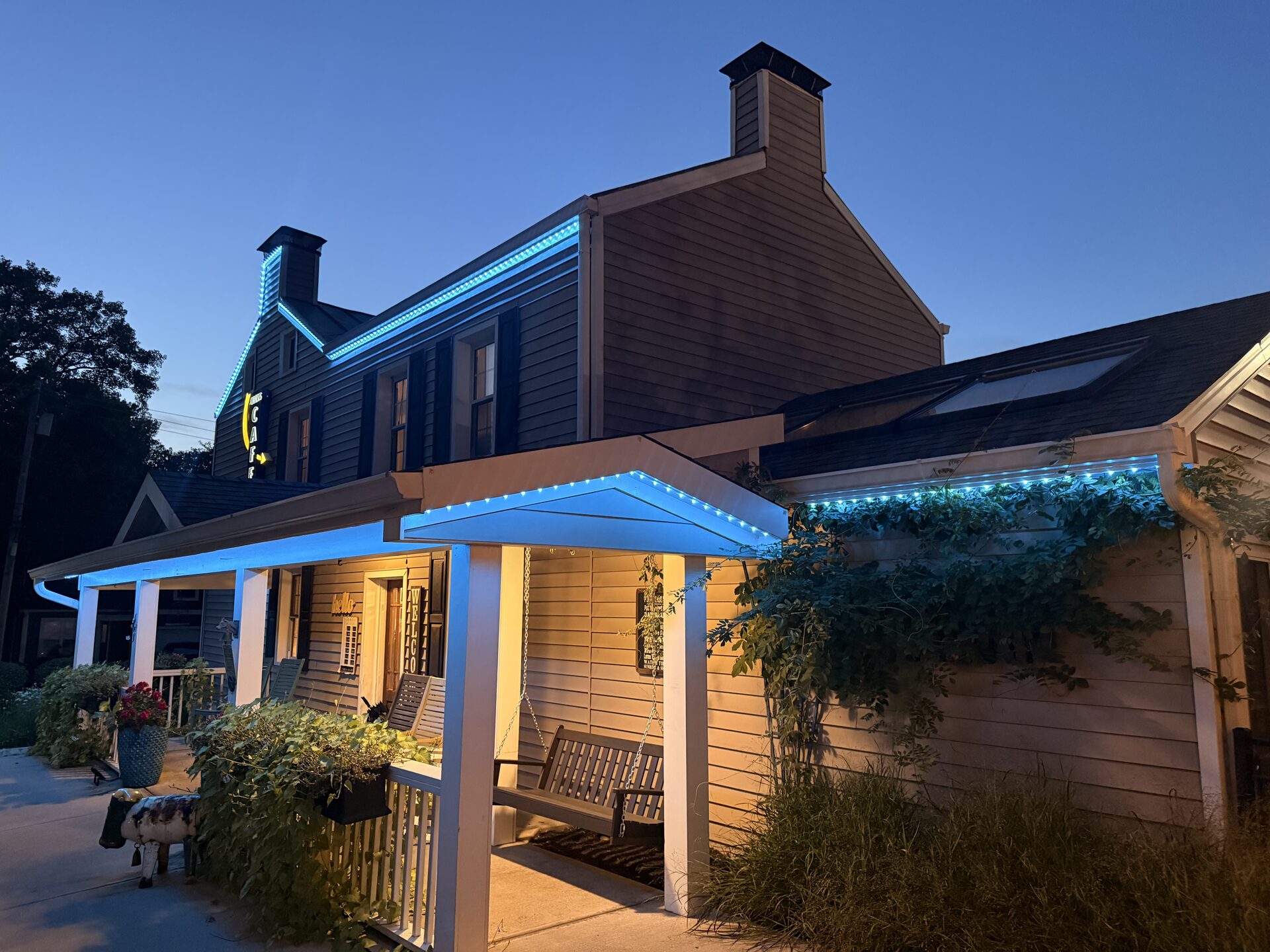 Cozy's porch roofline lit blue at dusk