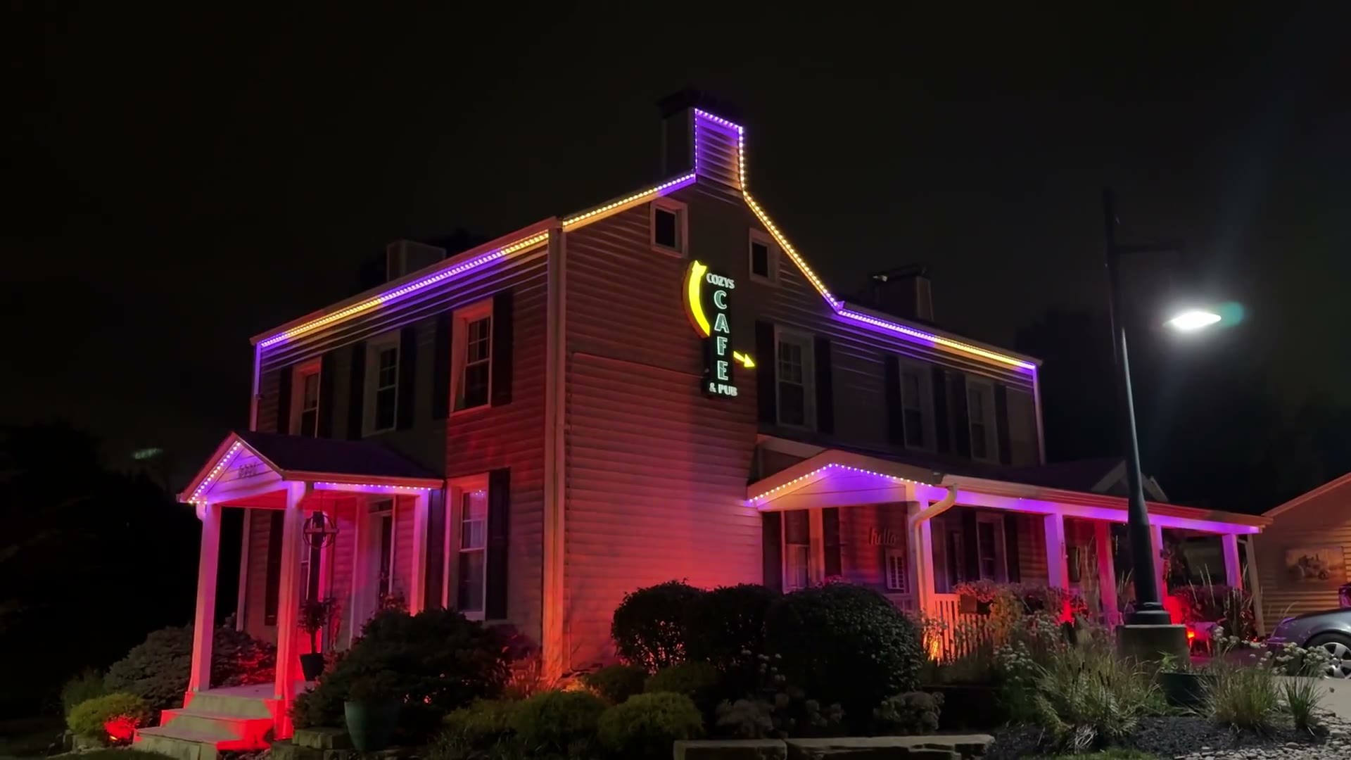 Cozy's Cafe & Pub roofline lit pink and red at night