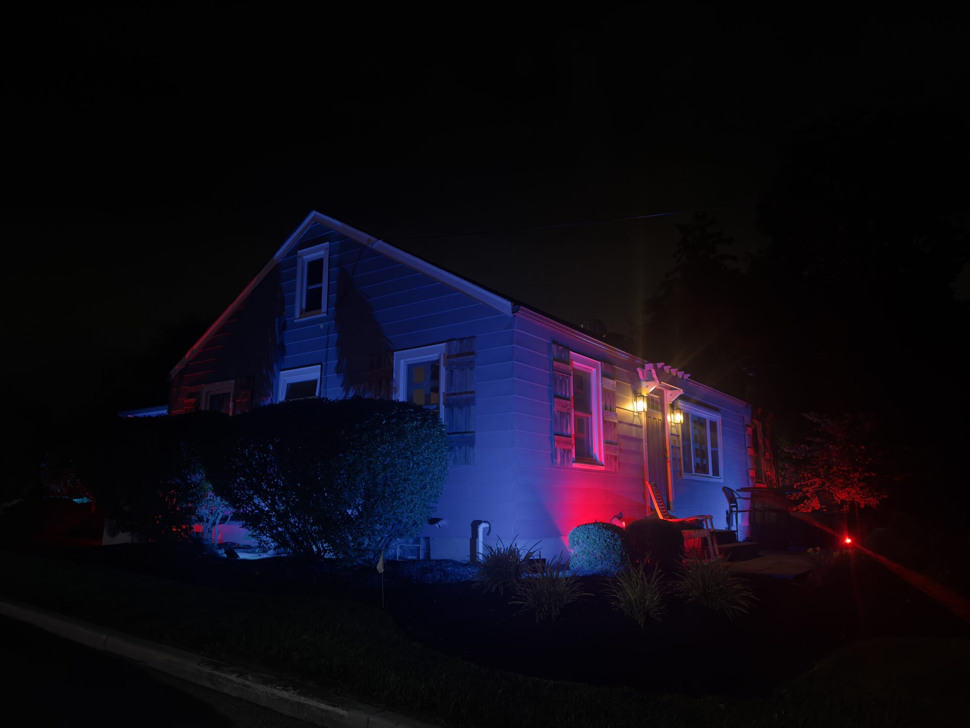 Cozy's second building with red and blue uplighting at night